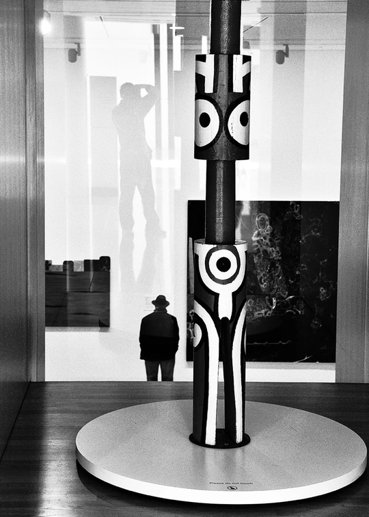 一张黑白照片 一个人站在一件雕塑旁边。