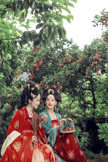 一对身着传统服饰的年轻女子在一个绿树成荫的花园里摆姿势