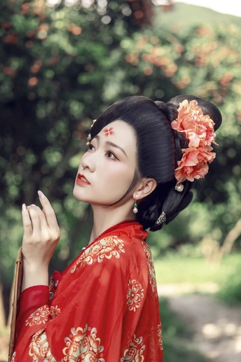 一位年轻女子穿着传统的红色连衣裙 头发上插着鲜花 在外面摆姿势