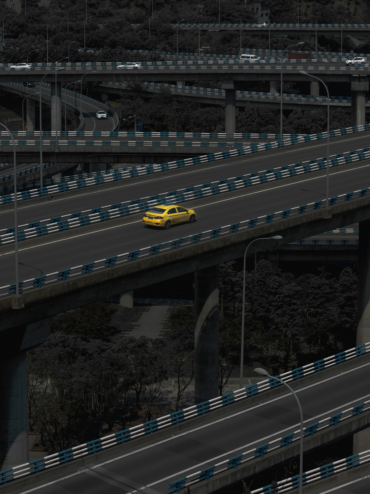 一辆黄色出租车在高速公路上越过一座桥 其他车辆在桥下行驶。