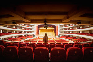 一个大型礼堂 有红色座椅 一个人站在舞台上。