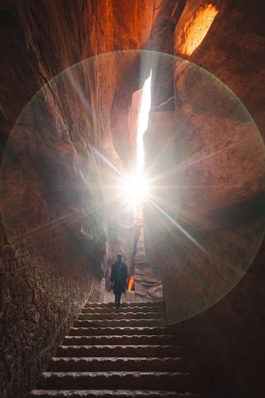 一个人走上楼梯 进入一个有阳光照射的隧道。