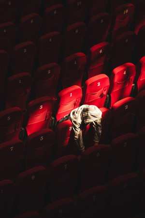 一个人站在一个空荡荡的带红色座位的剧院里