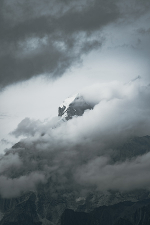 a mountain peak shrouded in clouds in the sky