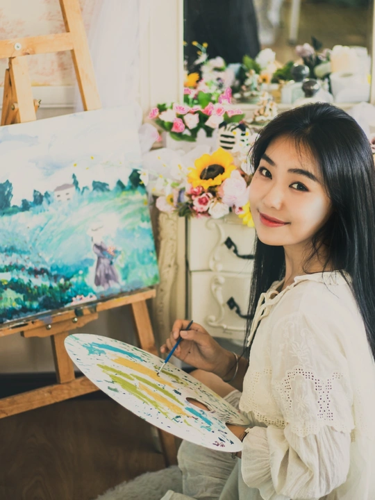 一个年轻的女人拿着画笔在画室的一幅画前的画布上画了一幅画