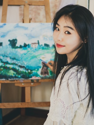 一位年轻女子站在画架前 在画布上画了一幅画