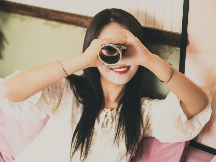 一个年轻的女人把杯子举到眼睛边看着相机