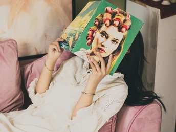 躺在床上的一位年轻女子把一本书捂在脸上