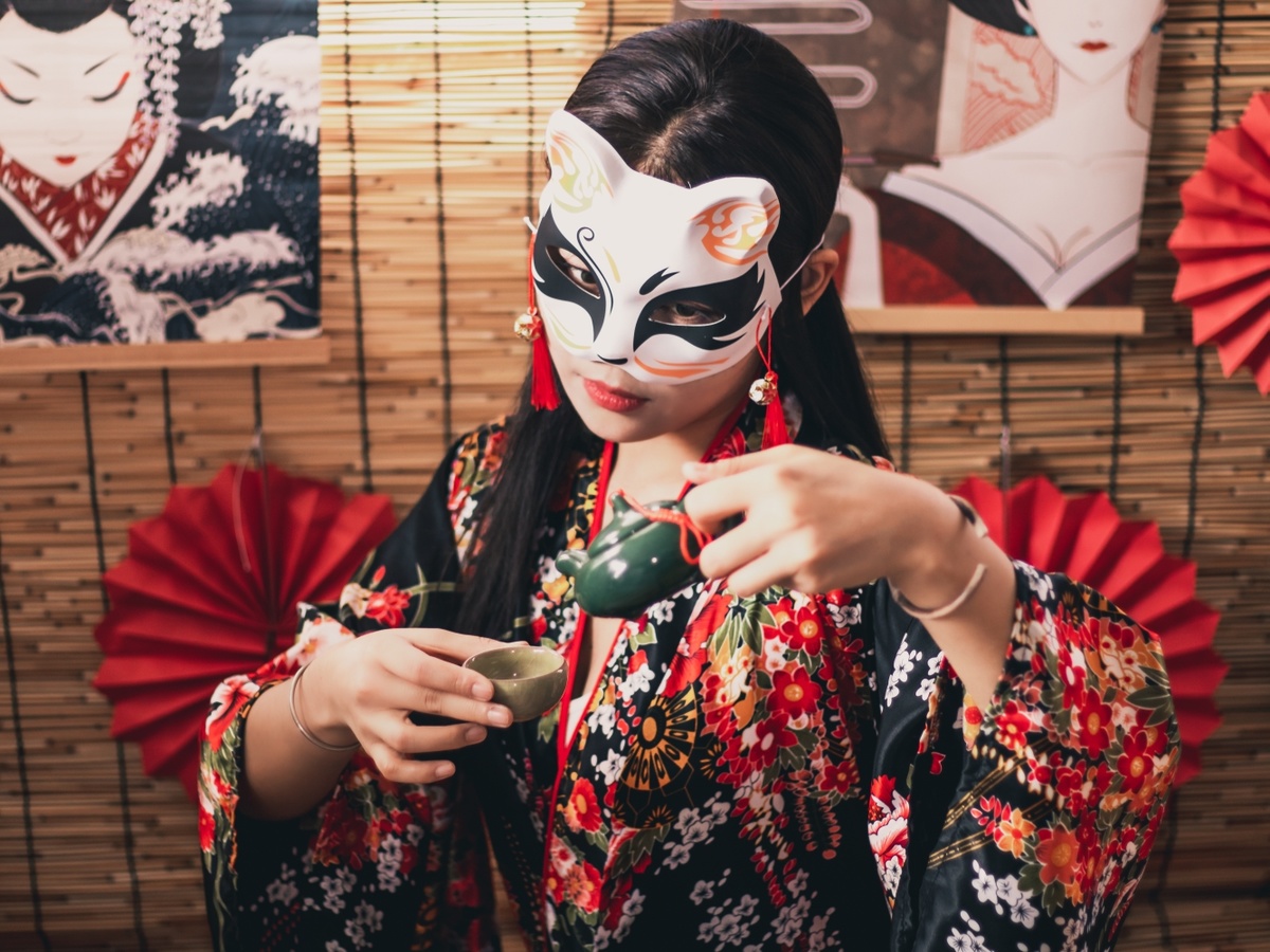 一位脸上戴着传统日本面具的年轻女子