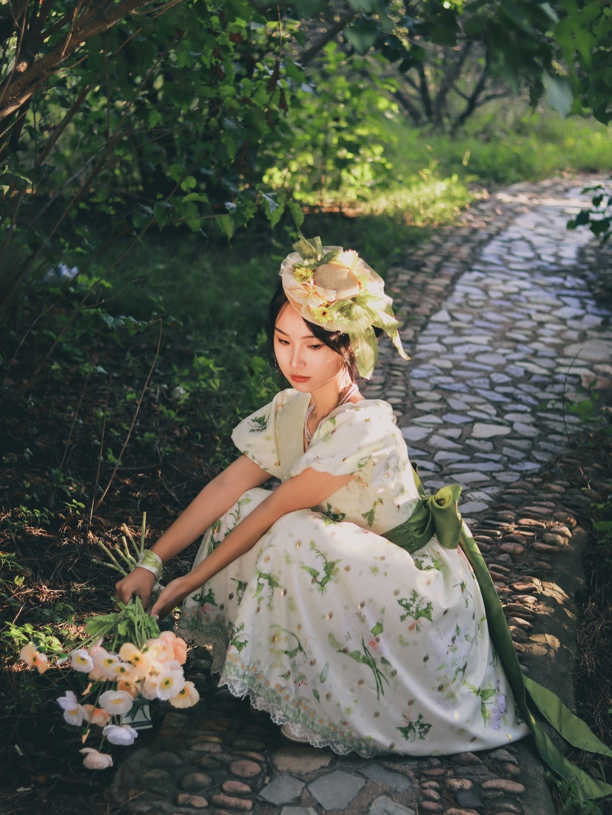 一个穿着漂亮连衣裙的年轻女子坐在花园的小路上