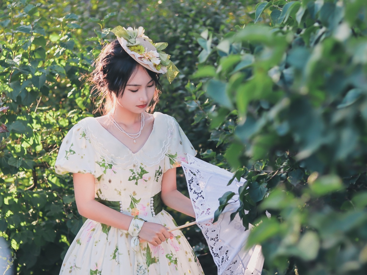 一个穿着白色连衣裙、戴着帽子的美丽年轻女子在花园里采花