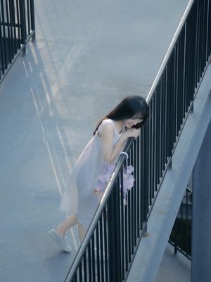 一个穿着白色连衣裙的年轻女子走下靠近围栏的楼梯