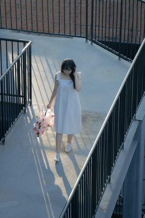 一个穿着白色连衣裙的小女孩拿着一束花走下楼梯