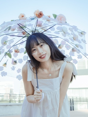 一个穿着白色连衣裙的年轻女子拿着一把上面有花的伞