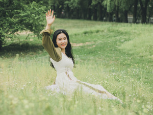 美丽的年轻女子穿着白色裙子坐在草地上
