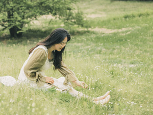 一位美丽的年轻女子坐在白色的花和草地上