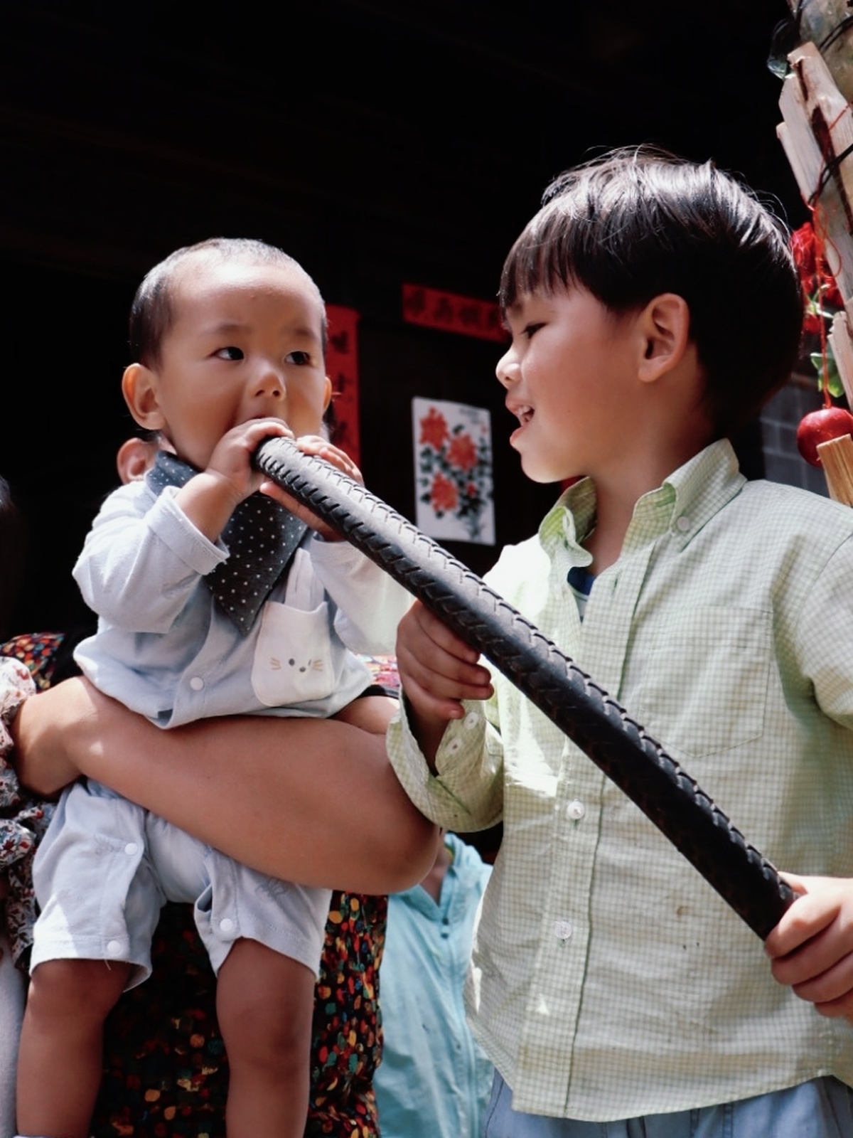 一个戴领带、嘴上拿着棒球棒的年轻人旁边站着一个拿着麦克风的小孩子。