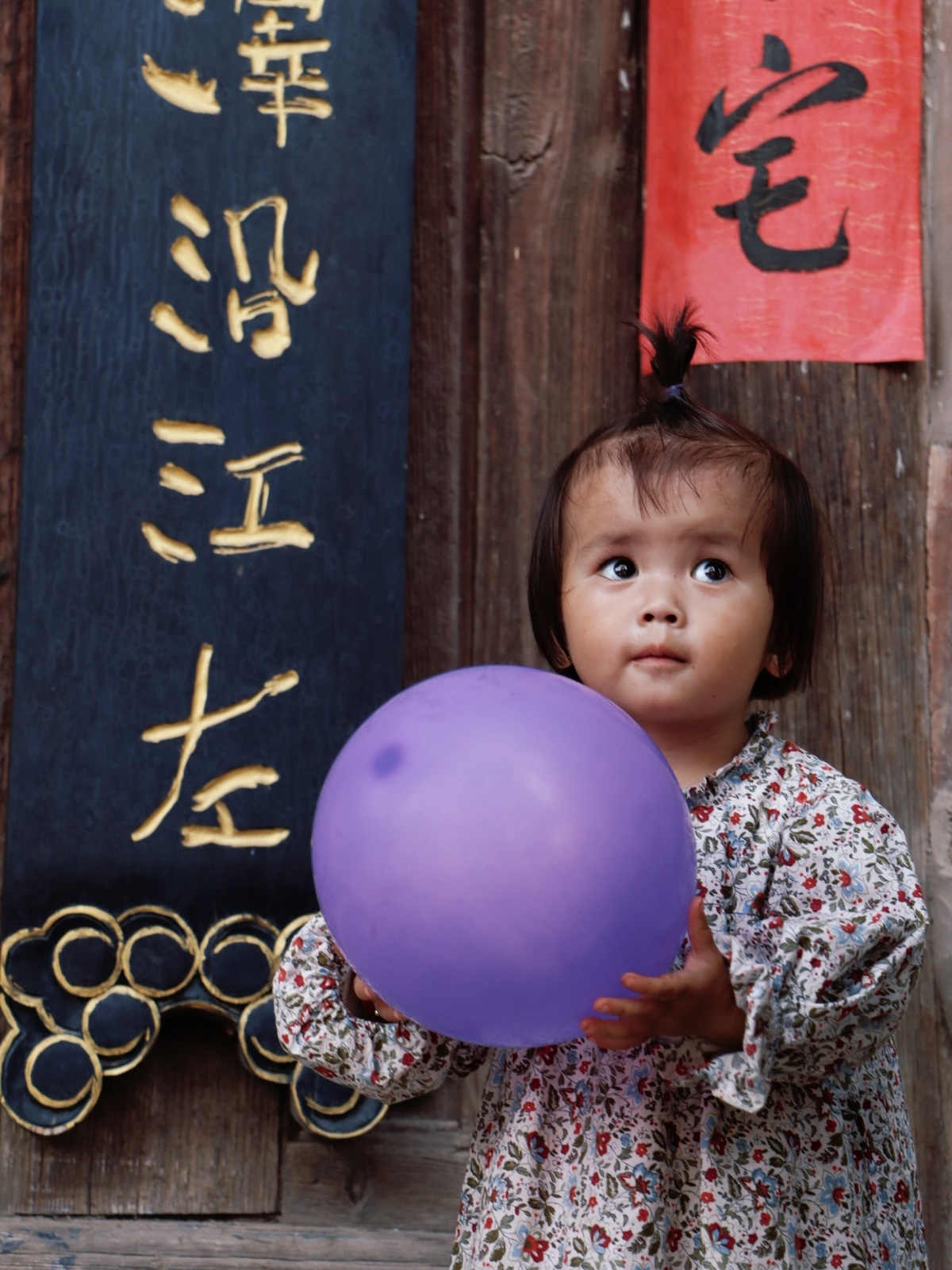 一个小女孩拿着一个紫色的球在玩一个小球。