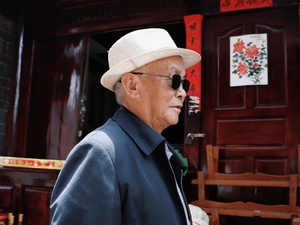 一个戴白帽子和太阳镜的老人走过一扇门