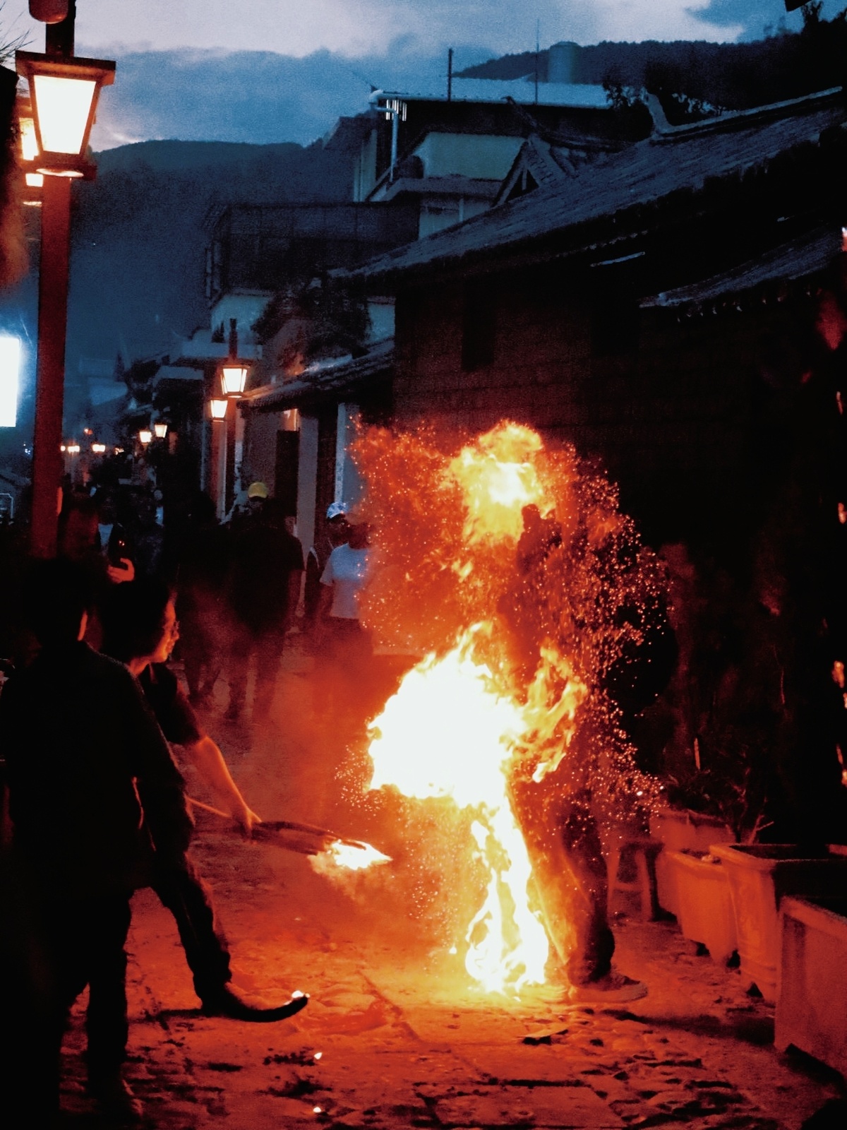 一个男人向街道上的大型篝火扔火。