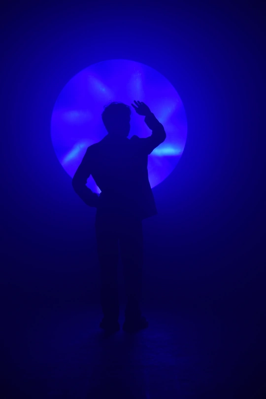 一个站在蓝色光线前的男人的黑暗图像