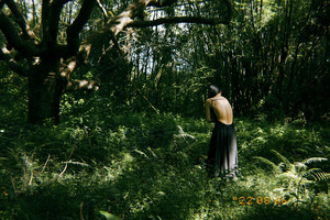 一个穿着黑色连衣裙的男人穿过绿树成荫的森林