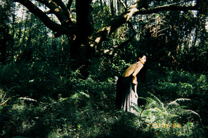 一个穿着黑色连衣裙的女人穿过一片树林 而一个男人站在树下