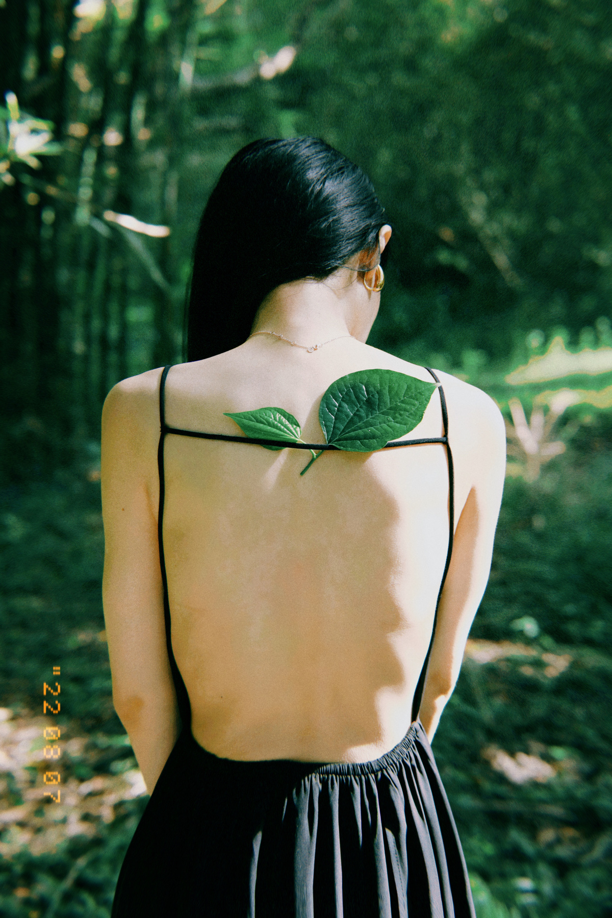 一个纹身的女人站在树林里 手里拿着一片树叶