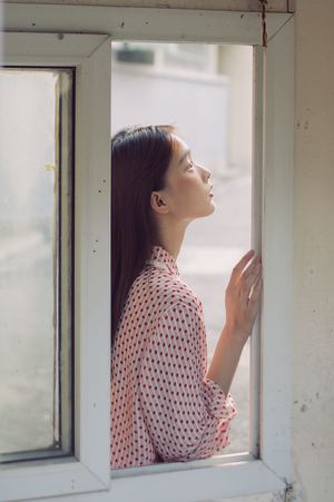 一位年轻女子正在窗口向外看