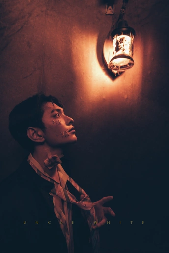 一个穿着西装打领带的年青男子站在一个光线昏暗的房间里 墙上有一个灯泡。