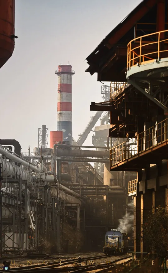 蓝色火车在靠近工厂的铁路轨道上行驶