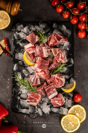 生肉、蔬菜、香草和香料在深石背景的冰块上 配以柠檬、番茄和胡椒。