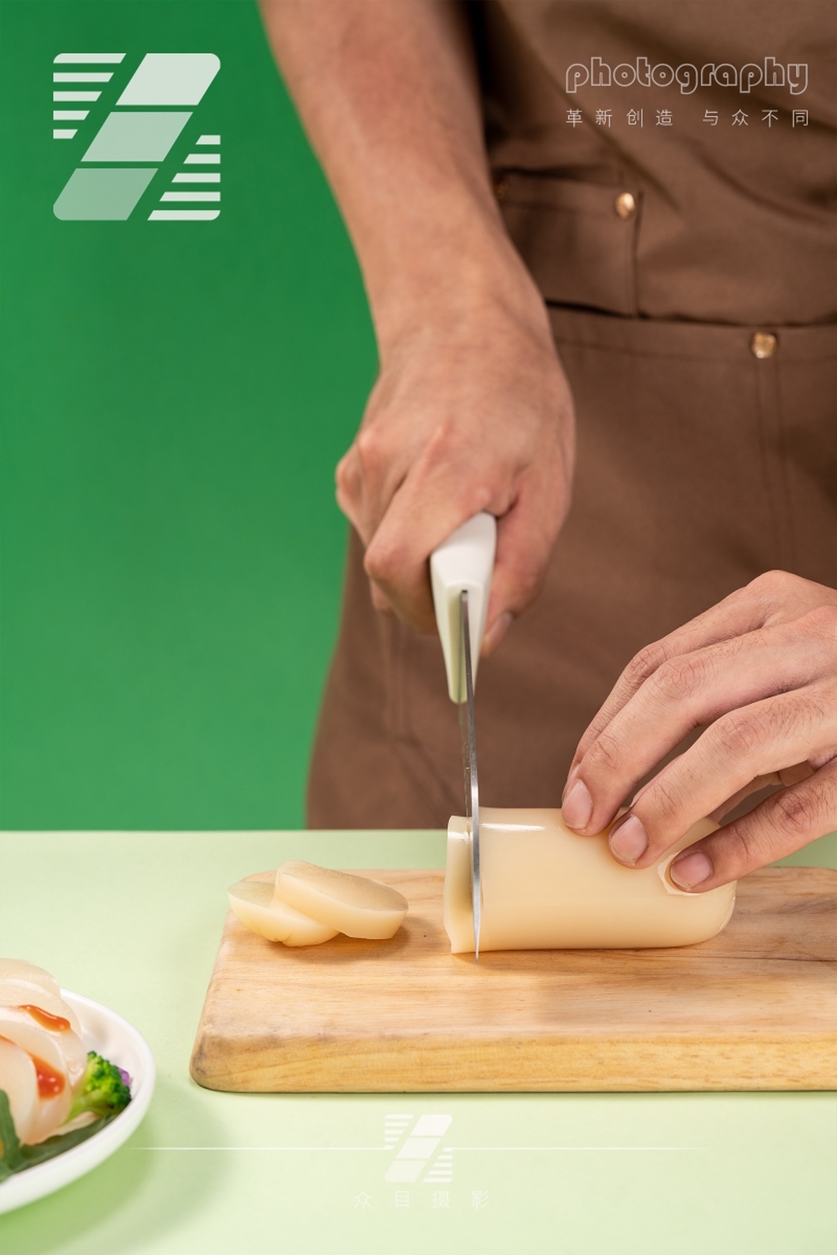 一个人正在一块小木板上切着一些奶酪 桌子上放着一盘蔬菜。