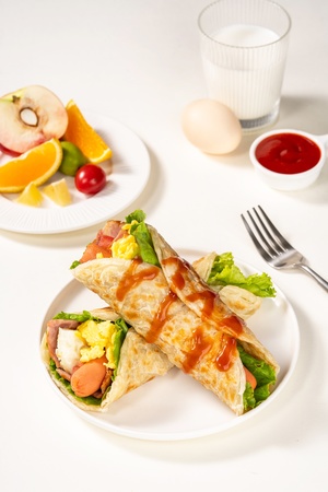 一个带有食物的白色盘子 其中包括一份沙拉、橙子、一小杯酱汁和一把叉子。