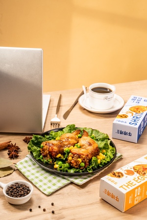 一盘食物放在木桌旁边 旁边有一台笔记本电脑和一杯咖啡。