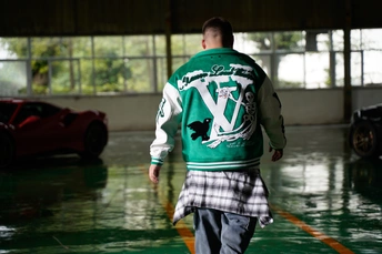 一个穿着绿色和白色格子伞的年轻人穿过一个被淹的的车库。