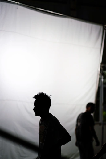 一个站在白色背景前的男子 背后有白色光线 后面有人们行走。