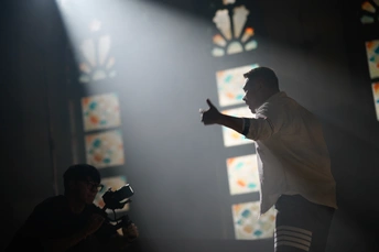 一个站在由彩色玻璃窗照射的房间里 舞台上冒出烟雾的男人带着相机。