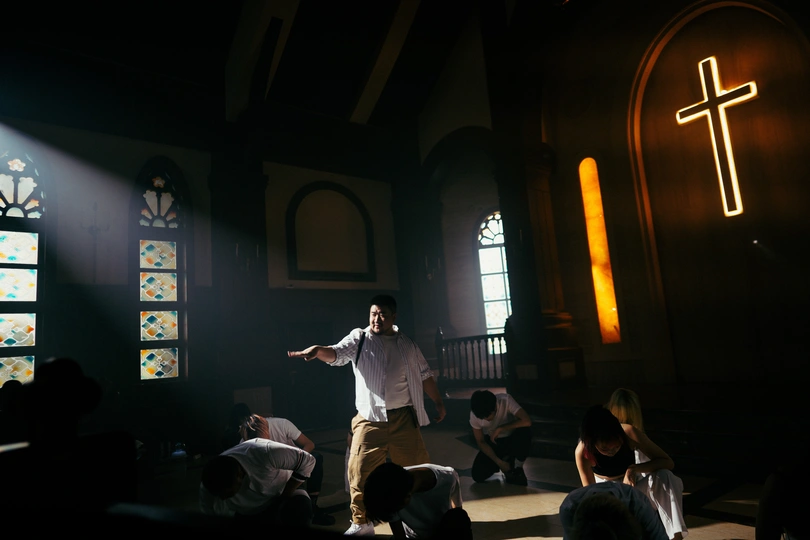 一个站在光线昏暗的房间里的舞台上 有彩色玻璃窗的男人