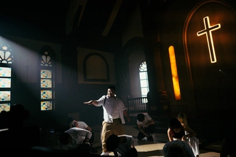 一个站在光线昏暗的房间里的舞台上 有彩色玻璃窗的男人