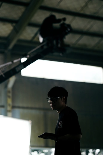 戴眼镜的男子正在一座建筑物里看着笔记本电脑