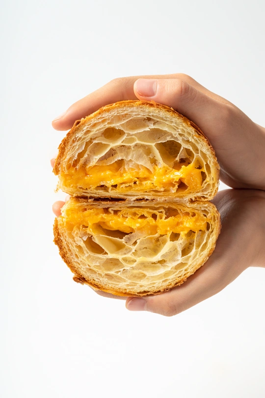 一个人拿着一个带鸡蛋和奶酪的面包