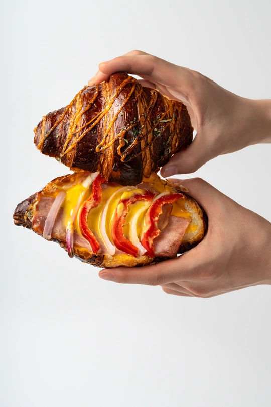 一个人拿着三明治 里面有肉、奶酪、苹果和面包。