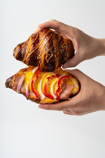 一个人拿着三明治 里面有肉、奶酪、苹果和面包。