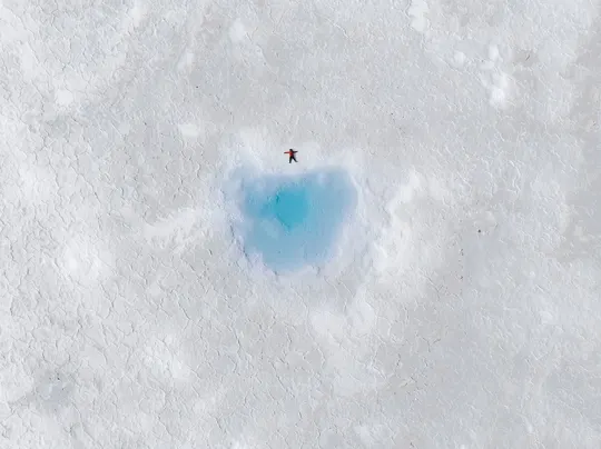 雪中一个小洞 蓝色的水 一个人在冰上