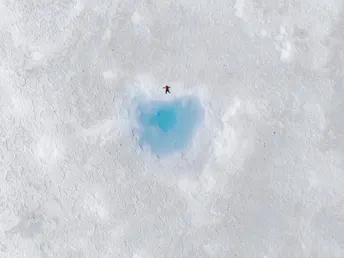 雪中一个小洞 蓝色的水 一个人在冰上