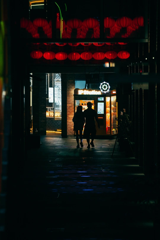 夜晚黑暗的街道 人们走在人行道上 还有一栋挂着红色霓虹灯的建筑