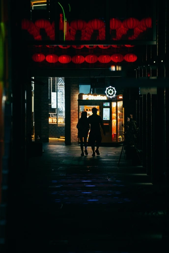 夜晚黑暗的街道 人们走在人行道上 还有一栋挂着红色霓虹灯的建筑