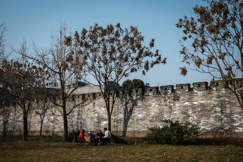 坐在老墙边的长椅上的人们