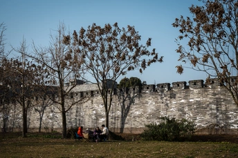 坐在老墙边的长椅上的人们